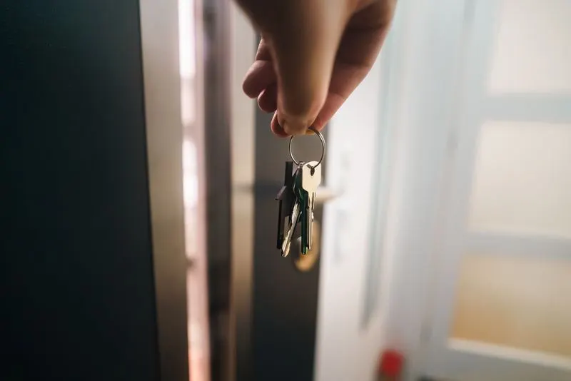 Mão com molho de chaves numa porta de entrada iluminada